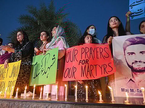 Activists of Pakistan Muslim League Nawaz (PMl-N) hold placard and pictures of six Pakistan military personnel who were killed in a helicopter crash during flood relief operations during a ceremony to pay tribute, in Lahore on August 6, 2022.