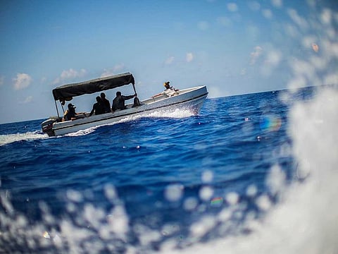 Migrants sail a fiberglass boat as they are assisted by Spanish NGO Open Arms crew members during a rescue operation south of the Italian island of Lampedusa in the Mediterranean sea, Tuesday, Aug. 9, 2022.