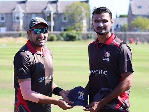 UAE pacer Zahoor Khan handing over the cap to debutant Sabir Ali before the ICC Men's Cricket World Cup League 2 match against Scotland in Aberdeen on Wednesday.