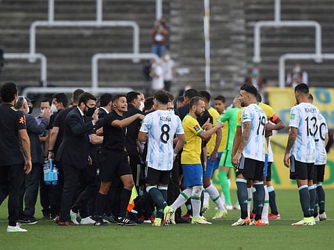 Players and officials are seen on the pitch as play is interrupted after Brazilian health officials objected to the participation of three Argentine players they say broke quarantine rules during the qualifiers in Sao Paulo.
