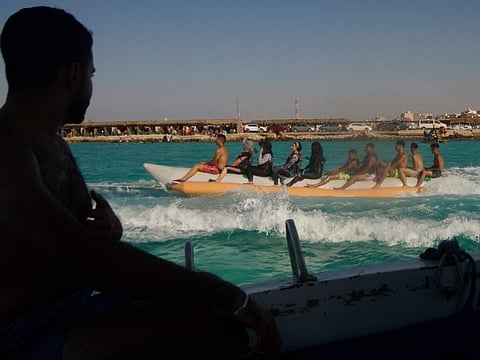 Egyptian holiday-makers ride on a banana boat at the beach of the Mediterranean city of Marsa Matrouh, 430km northwest of the capital, Cairo, on August 13, 2022.