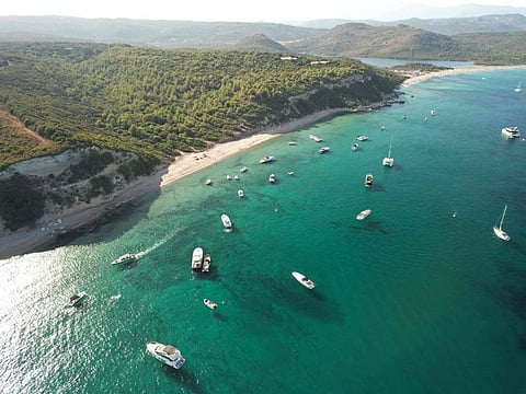 An aerial view shows boats moored in front of Ballistra beach in the Sant'Amanza bay in Bonifacio on August 16, 2022 on the French Mediterranean island of Corsica.