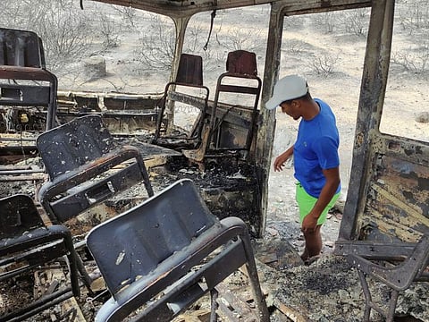 A man watches a charred van in a village of the region of El Tarf, near the northern Algerian-Tunisian border, Thursday, Aug.18, 2022.