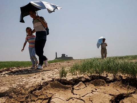 People walk across a dried-up section of Poyang Lake that is facing low water levels due to a regional drought in Lushan, Jiangxi province, on August 24, 2022.