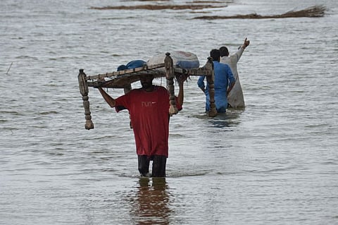 A villager carrying a 'charpai', a traditional bed, wades through flood waters following monsoon rainfalls in Jaffarabad district in Balochistan province on August 24, 2022.