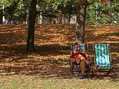 A man sits on a deckchair among brown leaves fallen from the trees in St James' Park in London, on August 24, 2022.
