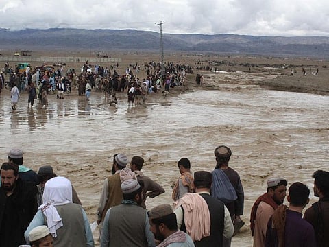 People gather as they watch flooded mud water after heavy monsoon rainfall in the border town of Chaman in Balochistan province on August 25, 2022.