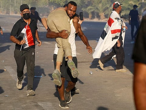 Supporters of Iraqi Shiite cleric Moqtada Sadr carry a wounded protester outside the Government Headquarters in the capital Baghdad's Green Zone. State TV said Iran had halted all flights to Iraq “until further notice because of the ongoing unrest”.