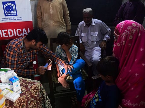 A doctor examines the skin of a girl affected by the floods at a free medical camp run by Al Khidmat Foundation on the outskirts of Sukkur, Sindh province.