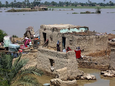 A woman holds her baby at her home surrounded by floodwaters in the Shikarpur district of Sindh Province, on Sept. 1, 2022.
