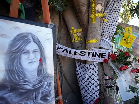 Yellow tape marks bullet holes on a tree and a portrait and flowers create a makeshift memorial, at the site where Palestinian-American journalist Shireen Abu Akleh was shot and killed in the West Bank city of Jenin, May 19, 2022.