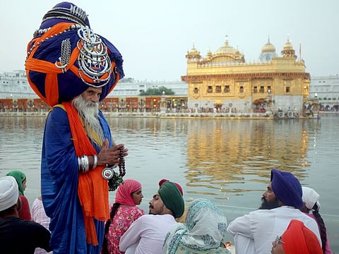 A Nihang Sikh wearing an oversized turban offers prayers at Golden Temple on the occasion of 418th anniversary of first installation of Guru Granth Sahib, in Amritsar, in a file picture.