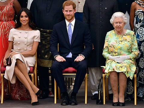 In this Tuesday, June 26, 2018 file photo, Britain's Queen Elizabeth, Prince Harry and Meghan, Duchess of Sussex pose for a group photo at the Queen's Young Leaders Awards Ceremony at Buckingham Palace in London.