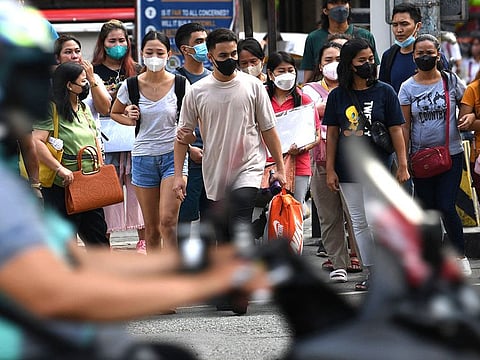 Face mask-clad pedestrians cross a road in Manila, Philippines.