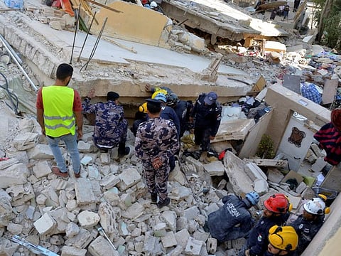 Rescuers search for survivors under the rubble of a collapsed building in Amman on September 14, 2022.