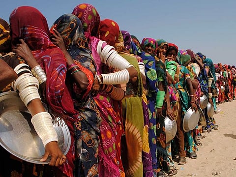 Women from flood-affected areas wait to get free food distributed by a charity, in Chachro, near Tharparkar, a district of southern Sindh province, Pakistan, Monday, Sept. 19, 2022.