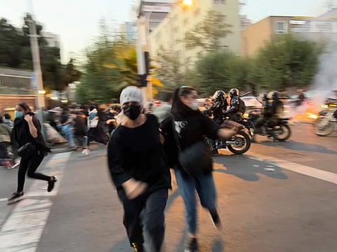 Women run away from anti-riot police during a protest of the death of a young woman who had been detained for violating the country's dress code, in downtown Tehran.