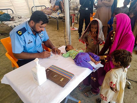 A woman receives medical assistance for her baby as she takes refuge at a relief camp in Sehwan.
