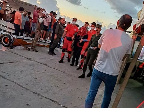 People take part in the rescue process of migrants in the port of Tartous, Syria.