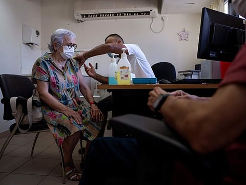 An Israeli woman receives the fifth Pfizer-BioNTech COVID-19 vaccine from medical staff at Clalit Health services in Tel Aviv, Israel, Thursday, September 22, 2022.