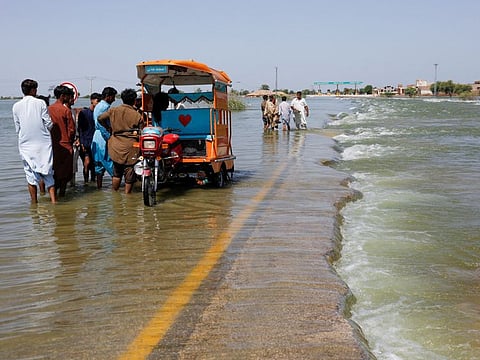 Displaced people stand on flooded highway, following rains and floods during the monsoon season in Sehwan, Pakistan, September 16, 2022.
