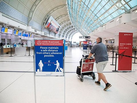 A man pushes a baggage cart wearing a face mask at Toronto Pearson International Airport.