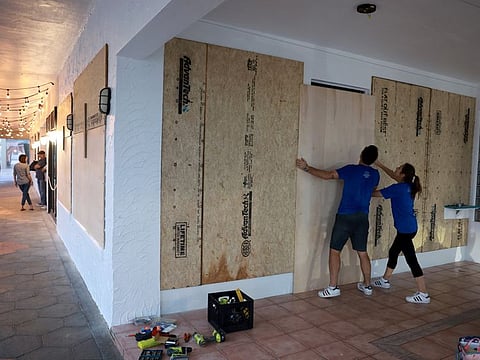 Luca Leguerchois (L) and Eglantine Leguerchois board up their Paradise Sweets store in preparation for Hurricane Ian on September 26, 2022 in St. Petersburg, Florida.