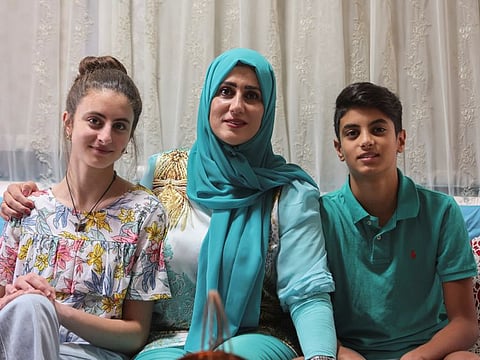 Public school teacher Claude Koteich poses for a picture with her son and daughter at their house in Deir Qubel.