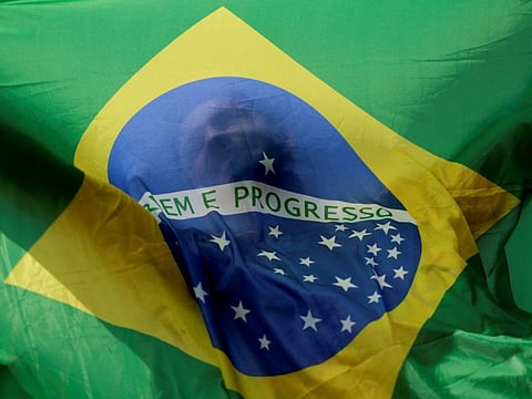 A man holds a Brazilian flag while taking part in a motorcade to show support for Brazilian President Jair Bolsonaro, in Brasilia, Brazil October 1, 2022.