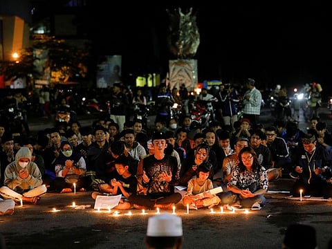 Arema football club supporters pray during a vigil outside the Kanjuruhan stadium to pay condolence to the victims in Malang, October 2, 2022.
