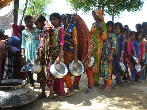 People gather to receive food handout in a camp in Sehwan.