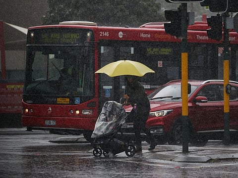 A pedestrian pushing a baby pram crosses a flooding intersection as heavy rains affect Sydney, Australia, October 6, 2022.