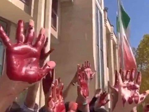 This image grab from a UGC video made available on twitter on October 9, 2022 shows Iranian students from the Faculty of Arts at Tehrans Azad University participating in a protest with their palms covered in red paint to symbolise blood.
