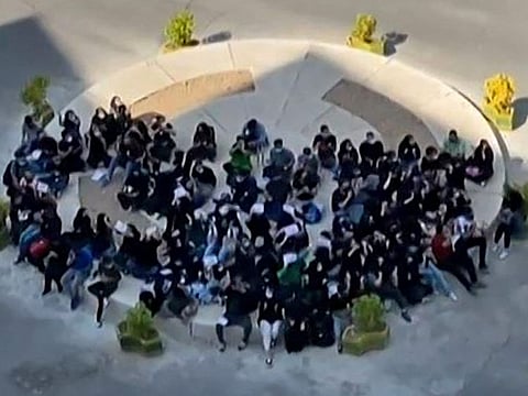 This image grab from a UGC video made available on twitter reportedly on October 12, 2022 shows Iranian students chanting "We don't want spectators, join us" as they gather on a roundabout near the Islamic Azad University in Tehran.