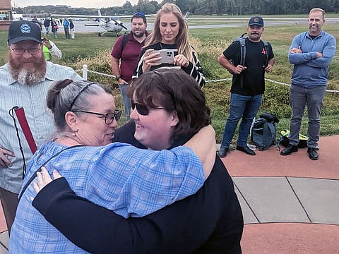 Kaiya Armstrong, right, hugs her mother, Kamla Armstrong, as her father, Mark, smiles. The Cessna she piloted across the country is behind them.