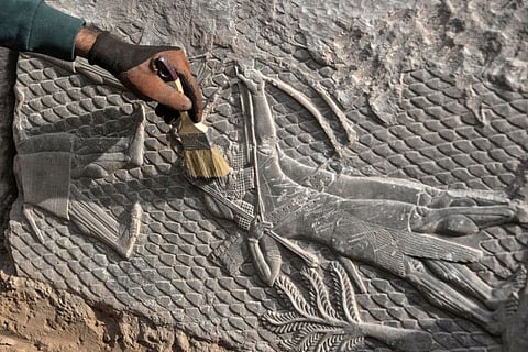 An Iraqi worker excavates a rock-carving relief recently found at the Mashki Gate, one of the monumental gates to the ancient Assyrian city of Nineveh, on the outskirts of what is today the northern Iraqi city of Mosul on October 19, 2022.
