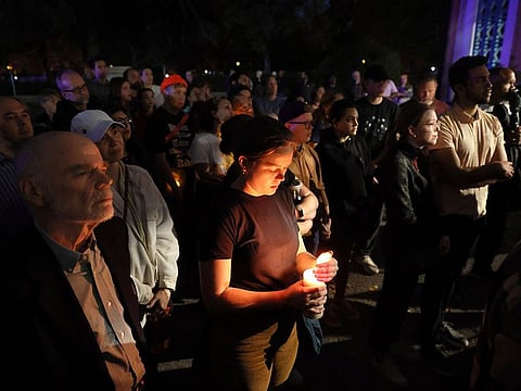 Marie Crane, center, holds a candle during a vigil in Tower Grove Park for the victims of a school shooting at Central Visual & Performing Arts High School in St. Louis on Monday, Oct. 24, 2022.