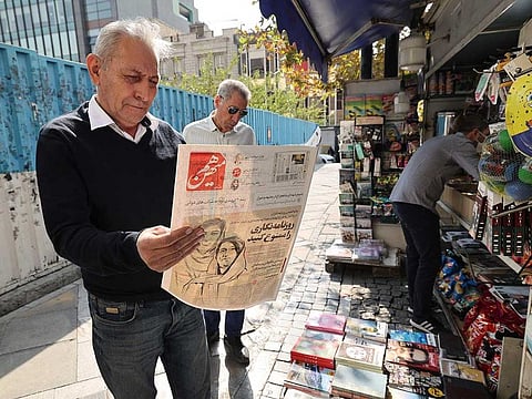A man checks in the Iranian capital Tehran on October 30, 2022, a copy of the Hammihan newspaper, featuring on its cover a headline mentioning the statement by the Tehran journalists' association, criticizing the detention by authorities of two journalists, Niloufar Hamedi and Elaheh Mohammadi (drawing on cover), who according to local media, helped publicise the case of Masha Amini.