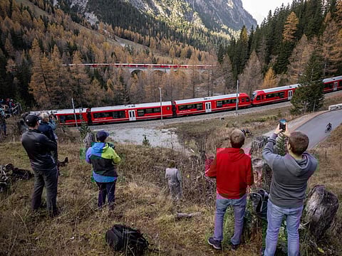Members of the public capture images as a 1910-metre-long train with 100 cars passes near Bergun, on October 29, 2022, during a record attempt by the Rhaetian Railway (RhB) of the World's longest passenger train, to mark the Swiss railway operator's 175th anniversary.