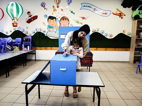 A little girl helps her mum cast her ballot on the day of Israel's general election in a polling station in Taibe, northern Israel,on November 1, 2022.