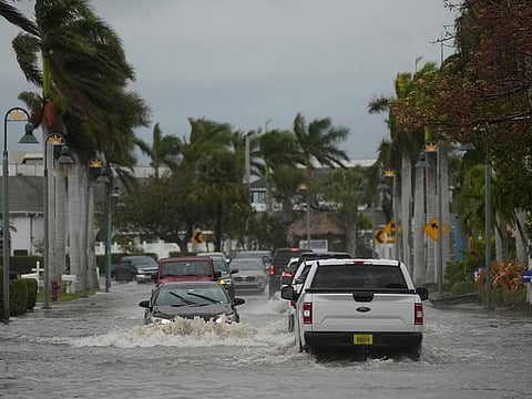 Drivers navigate a flooded street following the passage of Hurricane Nicole, in Fort Pierce, Florida.
