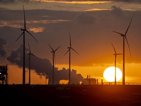 Steam rises from the coal-fired power plant with wind turbines nearby in Niederaussem, Germany.