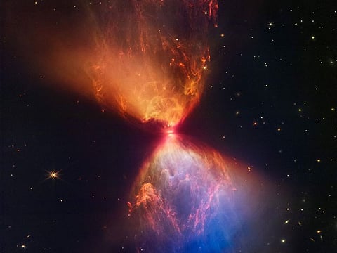 The Protostar within the dark cloud L1527 with ejections from the star above and below appear orange and blue in infrared view.
