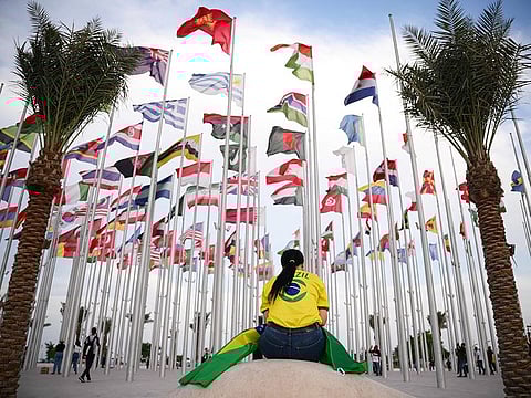 A woman sits at Flags square, in Doha on November 17, 2022, ahead of the Qatar World Cup football tournament.
