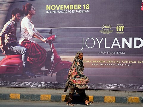 A woman walks past a promotional hoarding of an upcoming movie 'Joyland' displayed outside a cinema, in Lahore, on November 17, 2022.