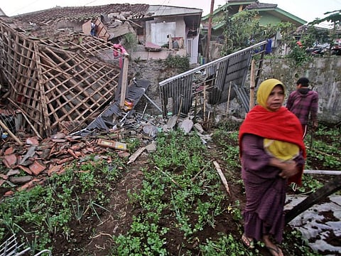 A woman walks past a house damaged by an earthquake in Cianjur, West Java, Indonesia, Monday, Nov. 21, 2022. A strong, shallow earthquake toppled buildings and collapsed walls on Indonesia's densely populated main island of Java on Monday, killing at least 56 and injuring hundreds as people rushed into the streets, some covered in blood and white debris. (AP Photo)