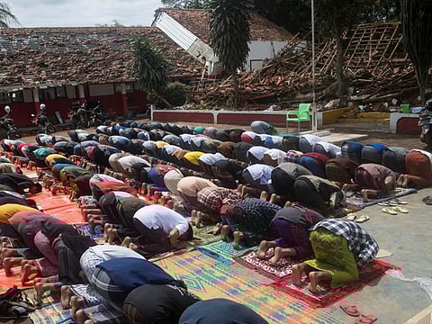 Men attend Friday prayers at an area affected by Monday's earthquake in Cianjur, West Java province, November 25, 2022.