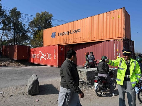A traffic policeman stands guard in front of a road blocked with shipping containers by authorities on the Islamabad Expressway, during the opposition party Pakistan Tehreek-e-Insaf (PTI) rally called "long march" in Islamabad on November 26, 2022.