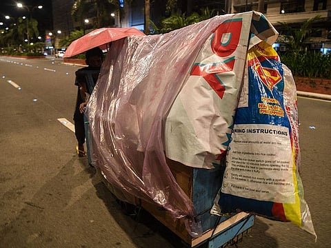 A homeless man pushing his pushcart 'home' as he looks for a place to park for the night along a road in Manila.