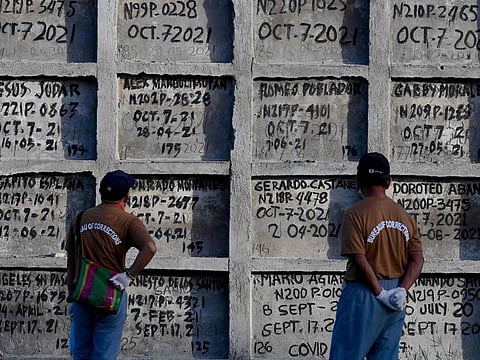 Prison inmates look at tombs during a mass burial of 70 unclaimed bodies of prisoners at New Bilibid Prison Cemetery in Muntinlupa, metro Manila on December 2, 2022.